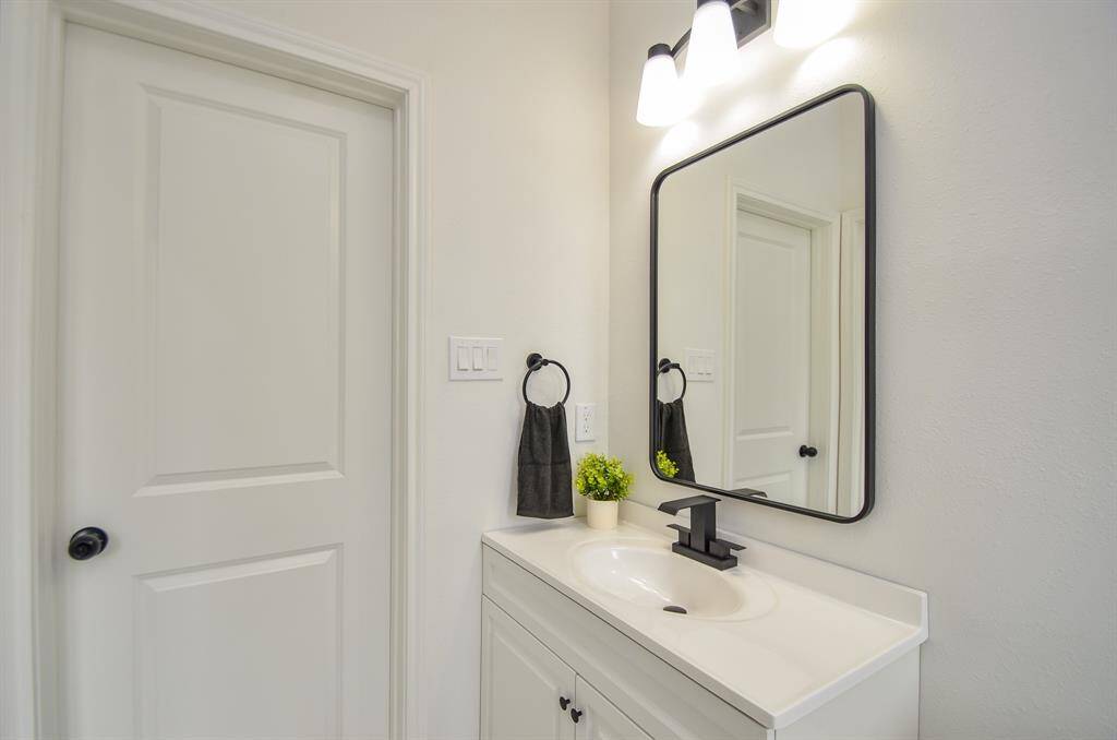 Jack and Jill bathroom is sleek and has black accents. Door opens to secondary bedroom.