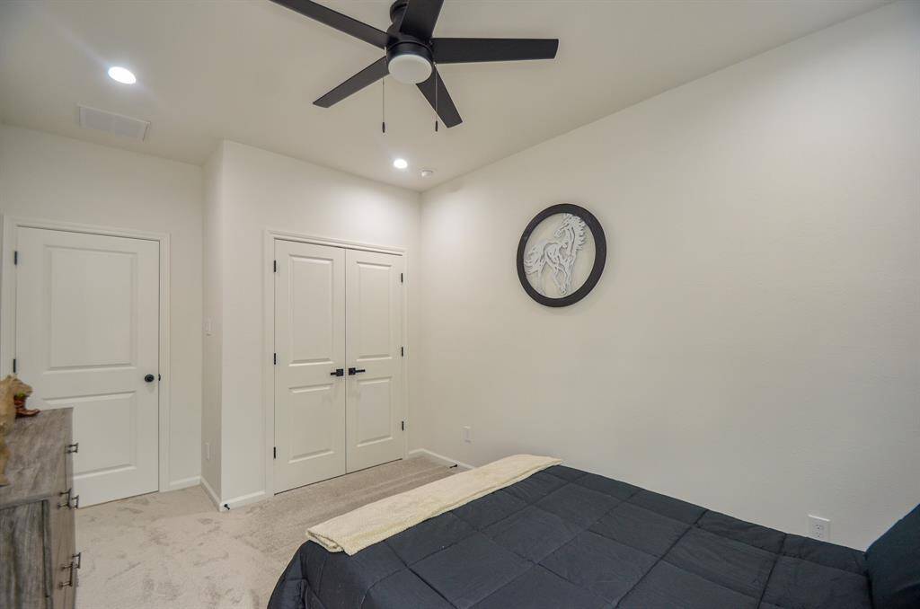 This secondary bedroom is staged as a bedroom has ceiling fan, a decorative wall piece, and ample closet space with double doors, creating a cozy and functional space.