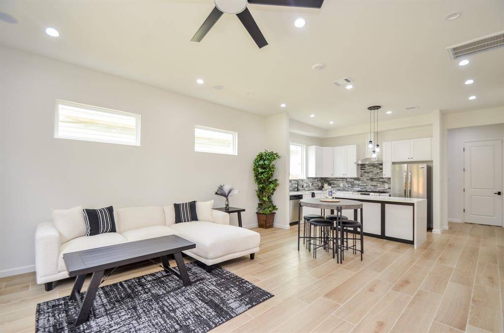 The spacious living room has a cozy sectional, a large ceiling fan, and wood-look flooring is ideally suited to entertaining.