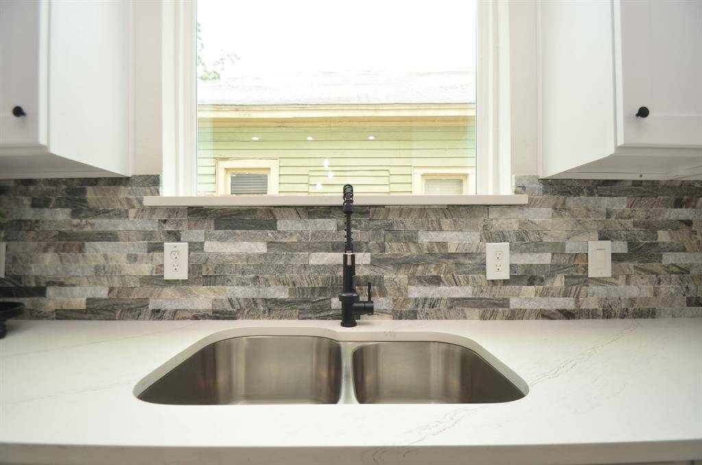 Modern design with large dual undermount stainless steel sink accented with black faucet and stone backsplash.  Window seal is Quartz like the countertops.