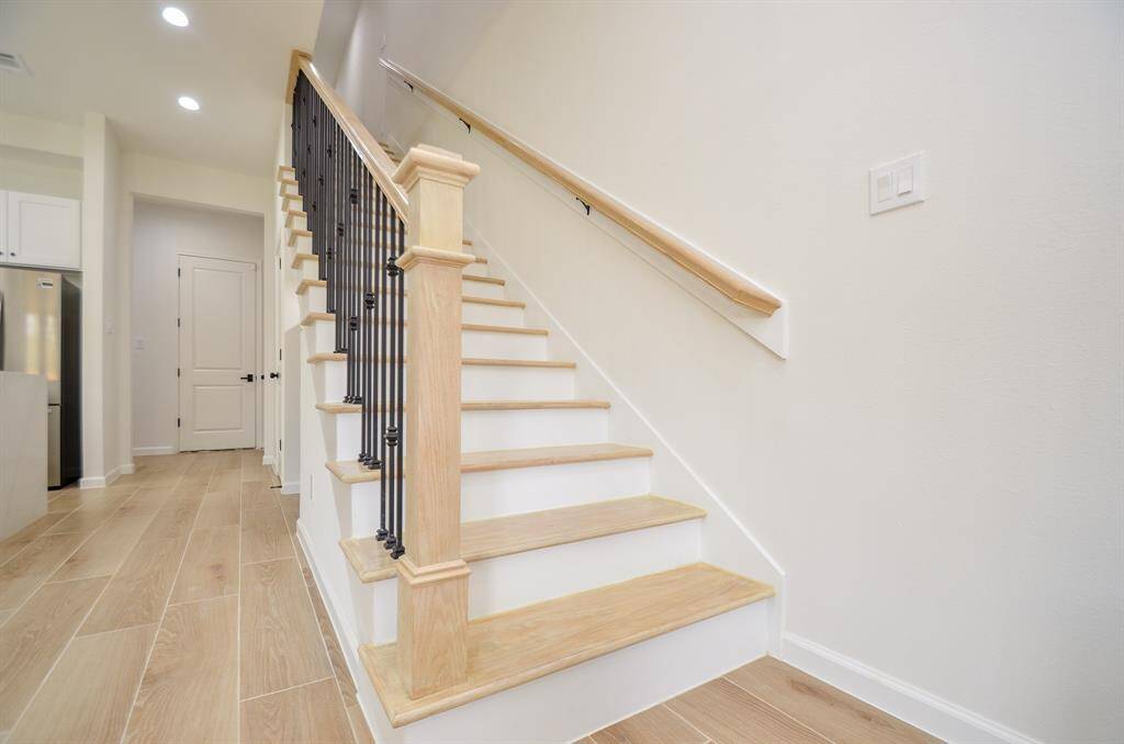 This photo showcases a modern interior with a wooden staircase leading to the upper floor. Garagedoor is in the background.