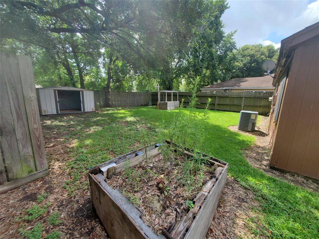 Huge backyard with a storage shed and several planter boxes for gardening.