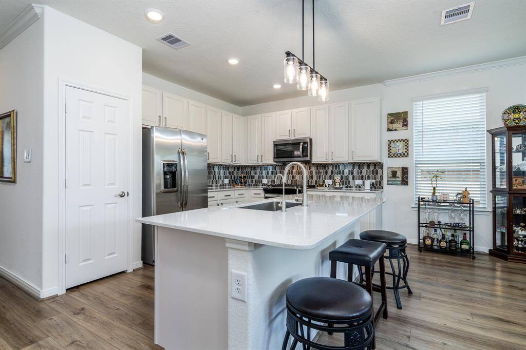 Gourmet kitchen with quartz countertop, modern backsplash, and stainless steel appliances