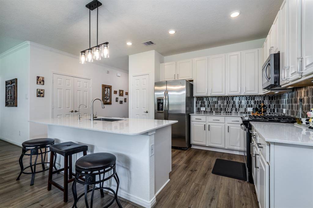 Gourmet kitchen with quartz countertop, modern backsplash, and stainless steel appliances