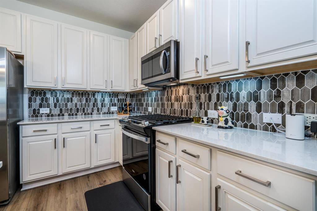 Gourmet kitchen with quartz countertop, modern backsplash, and stainless steel appliances