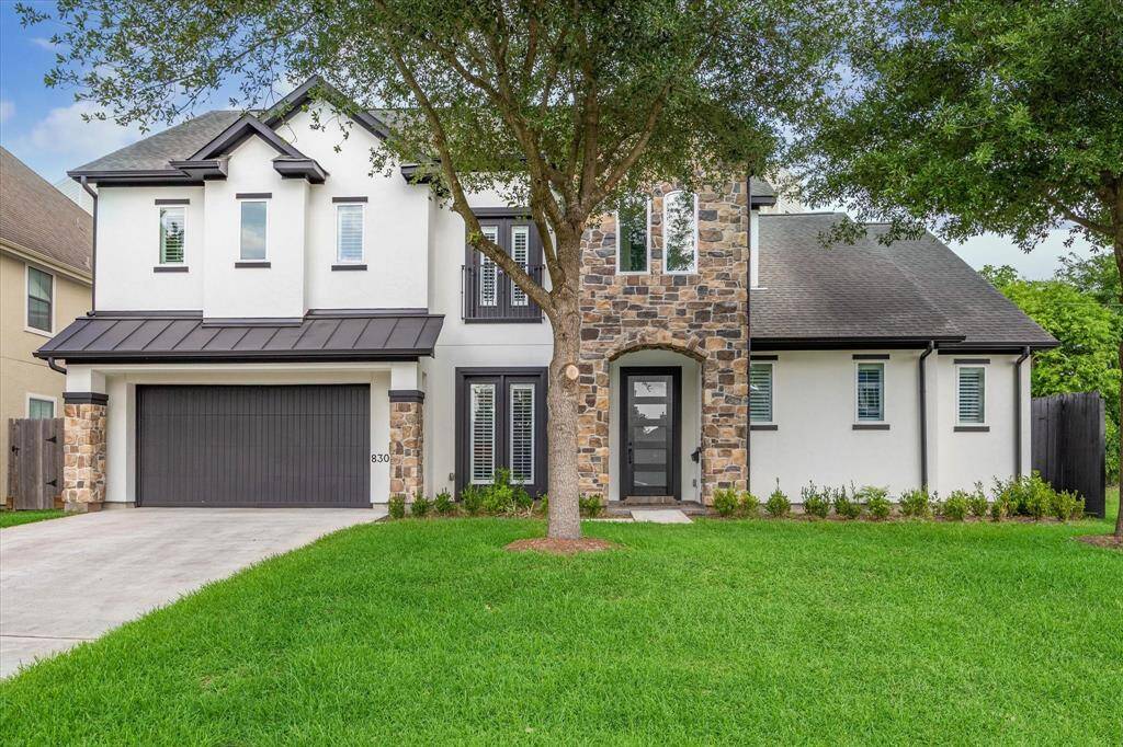 Modern two-story home in Knollwood Village featuring a stone-accented entry, sleek black trim, and a two-car garage. Clean lines and mature trees enhance the curb appeal.
