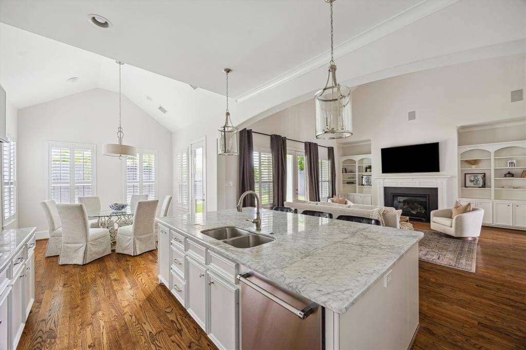 Bright kitchen with marble countertops, a large center island, and an open layout that flows into the living and breakfast areas.