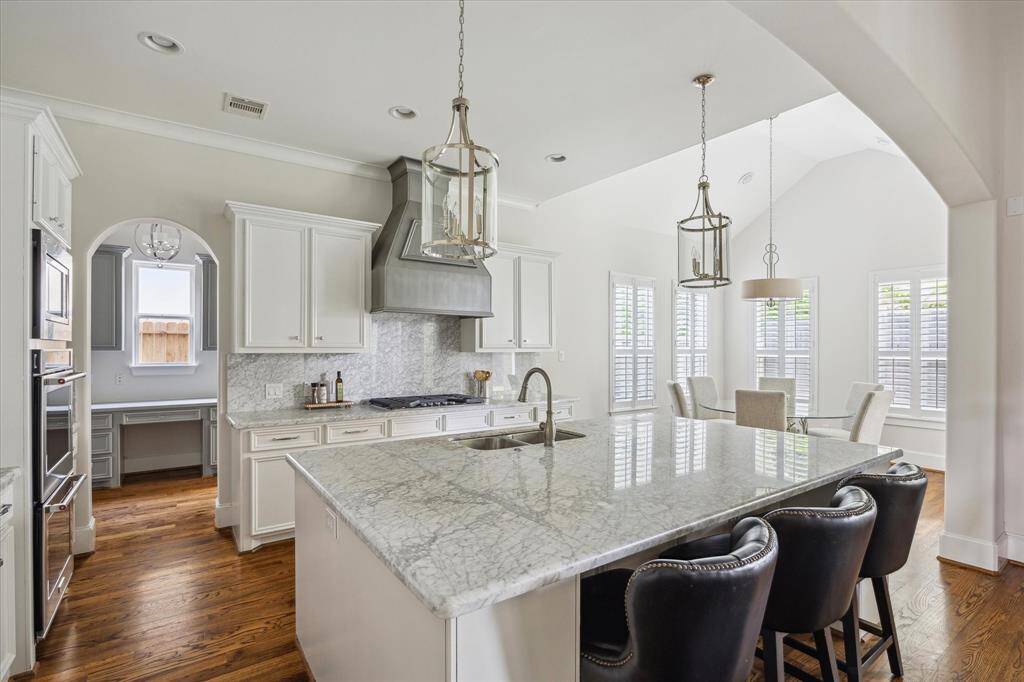 This kitchen features expansive marble counters and a large island with ample seating, ideal for casual dining and entertaining.