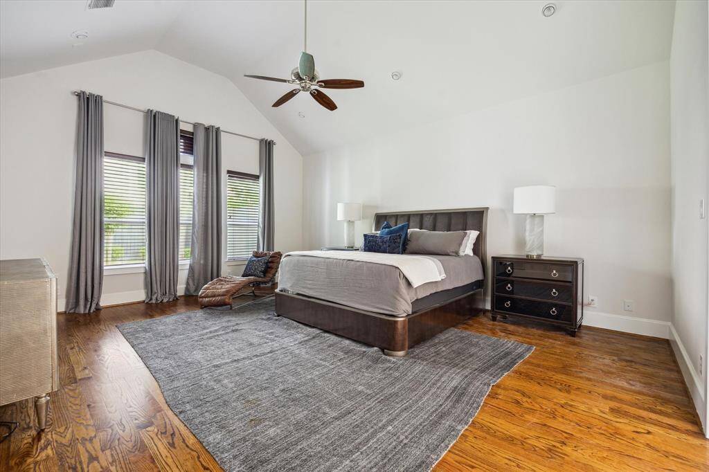 Spacious first-floor primary suite with hardwood floors, vaulted ceiling, and large windows offering natural light and backyard views.