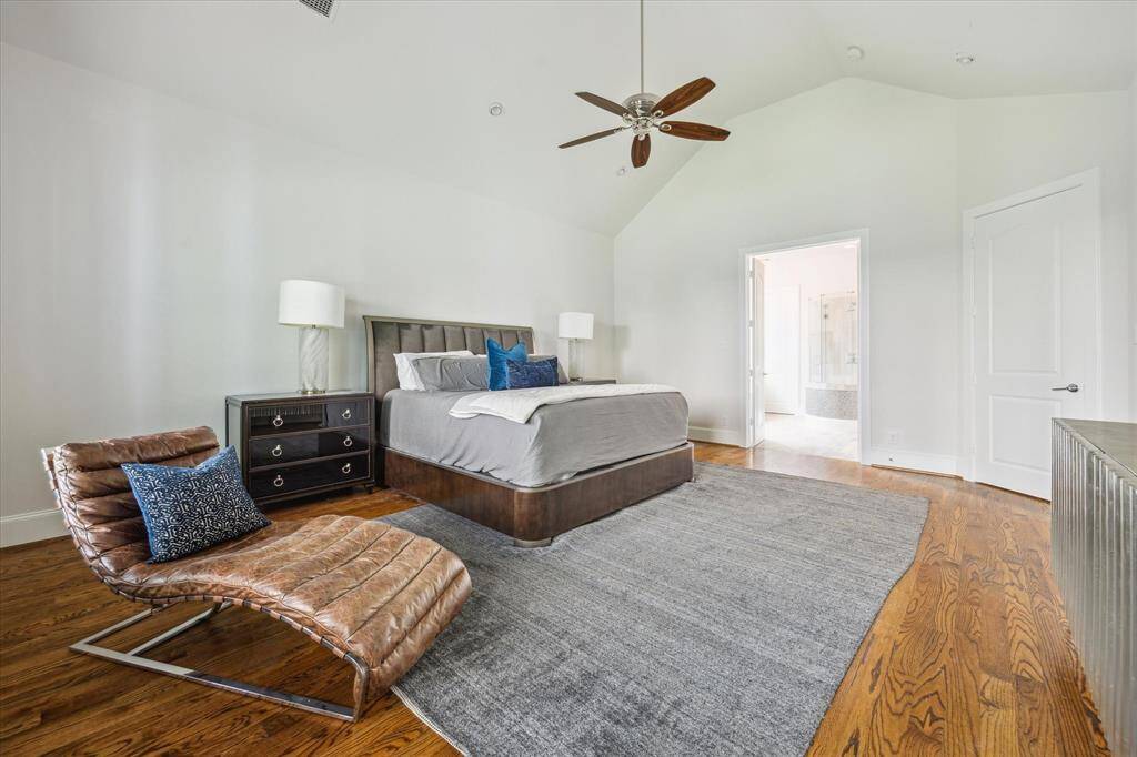 The first-floor primary suite offers generous space, hardwood floors, and soaring ceilings that enhance the open, airy feel.