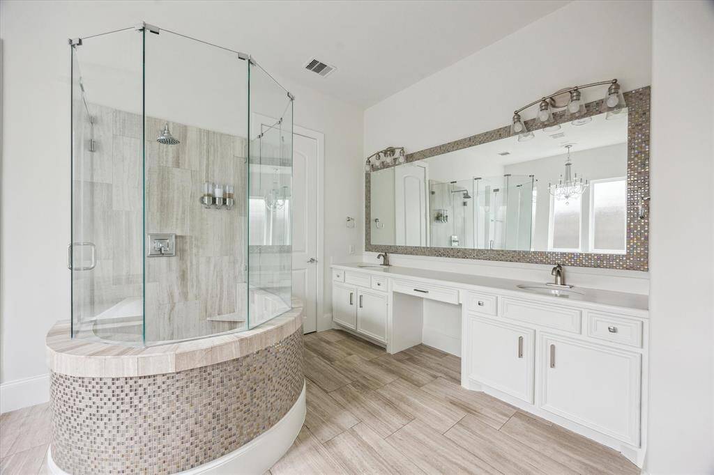 Elegant primary bathroom with a unique circular shower and tub combo, dual vanities, and a large framed mirror stretching across the wall.