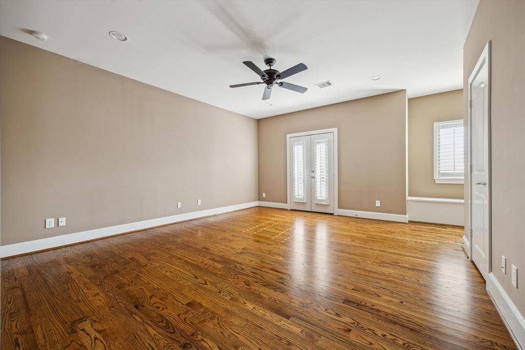 Spacious secondary bedroom with hardwood floors, French doors, and flexible layout—large enough to function as a game room or bonus space.
