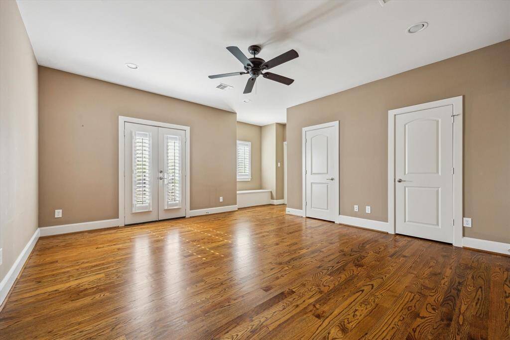 Generously sized secondary bedroom with hardwood floors, dual closets, and French doors—versatile enough to serve as a game room or media space.