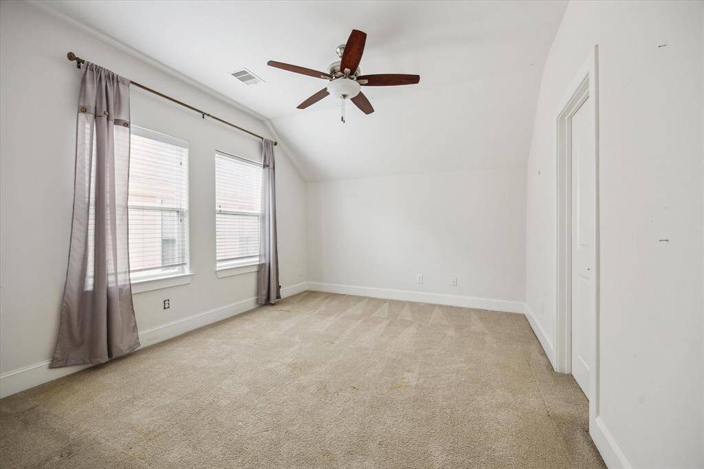 Secondary bedroom with sloped ceiling, neutral carpet, and double windows providing ample natural light.