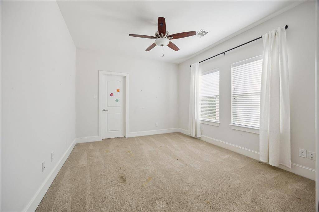 Secondary bedroom with light carpet, double windows for natural light, and a ceiling fan for added comfort.