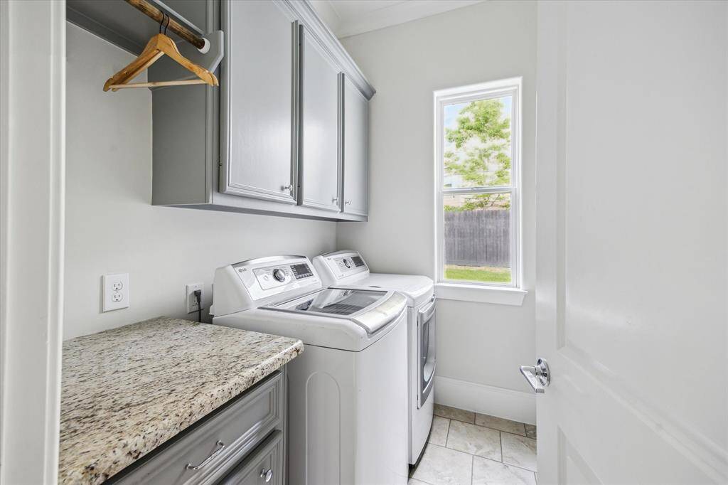 The utility room includes upper cabinetry, a granite folding counter, hanging space, and a window that brings in natural light.