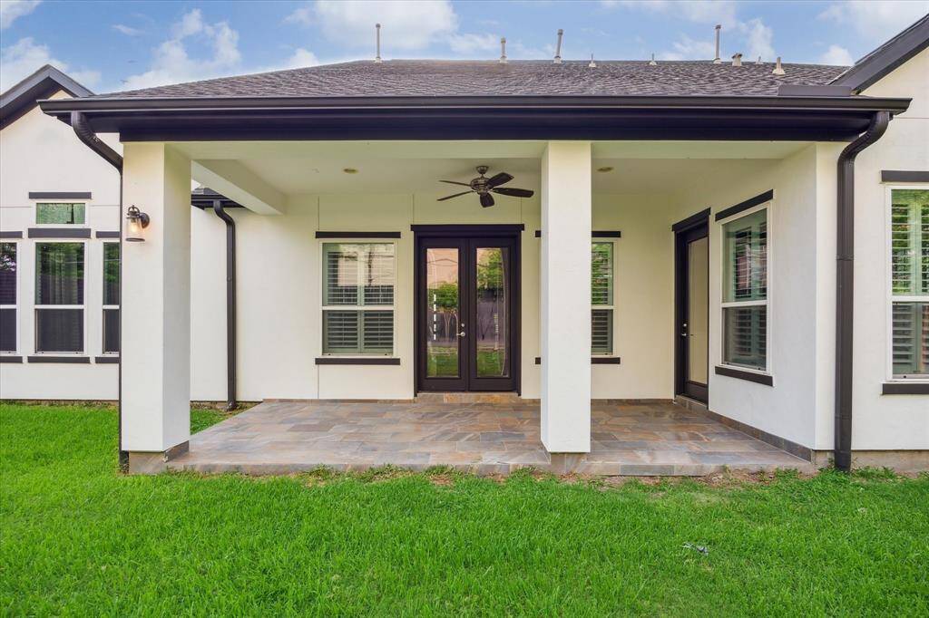 This back covered patio features a tiled floor, ceiling fan, and overhead lighting—ideal for relaxing or entertaining outdoors.