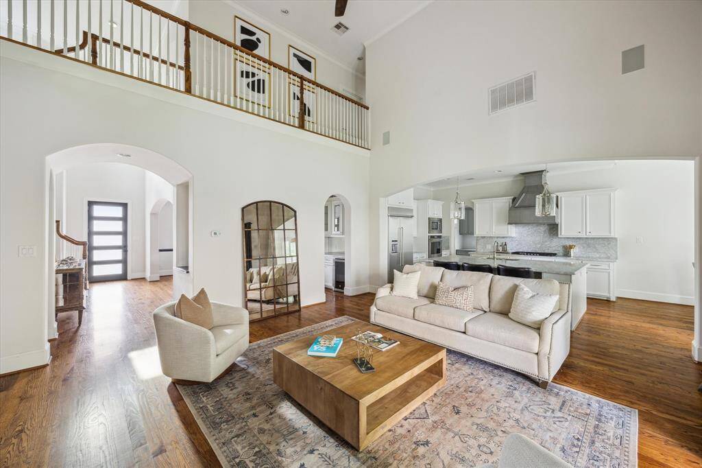 This open-concept family room features soaring ceilings, hardwood floors, and a view of the upstairs landing. It flows seamlessly into the kitchen and front entry.
