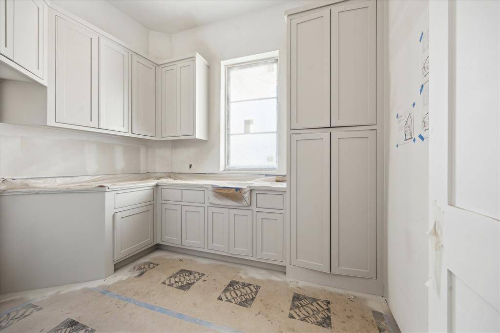 The laundry room with window for natural light, plenty of cabinetry and a broom closet! A sink, polished nickel fixtures and ratan hanging pendant will finish this space.