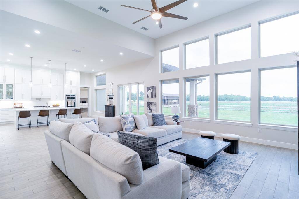 Spacious open-plan living area with abundant natural light, featuring a modern kitchen, large windows, and a cozy seating area with scenic views.