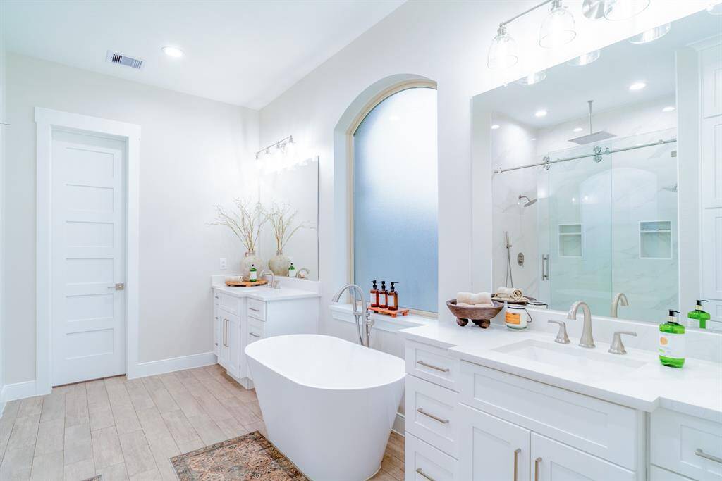 This bathroom features a modern, clean design with a freestanding tub, spacious double vanity, and a large walk-in shower. Bright and airy, it includes sleek fixtures and ample lighting.