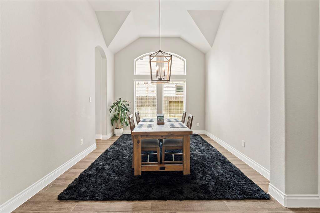 An elegant dining space with a vaulted ceiling and dramatic pendant light fixture. Large windows brighten the formal dining room up!