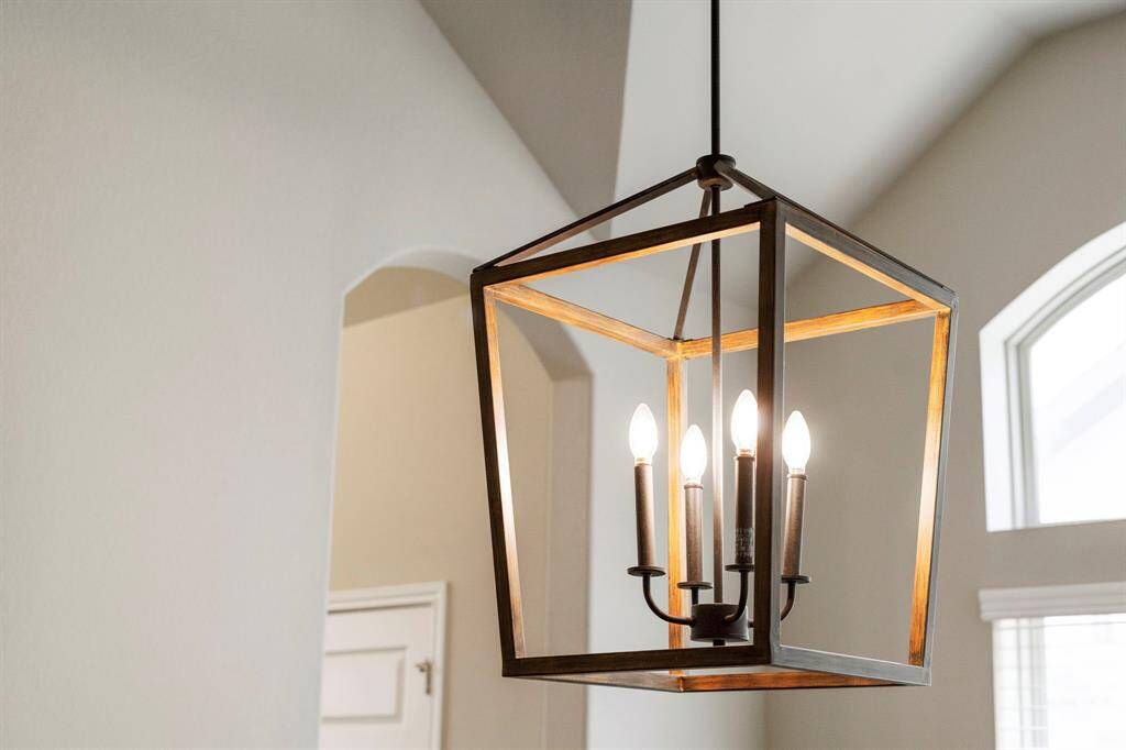 Close-up of a modern lantern-style chandelier in the dining space, complementing the high vaulted ceilings.