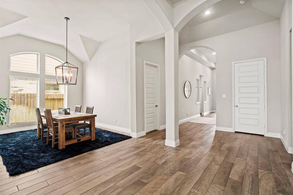 A broader perspective that captures the open layout between the dining room and entry hallway. Arched openings and column details define the space beautifully.