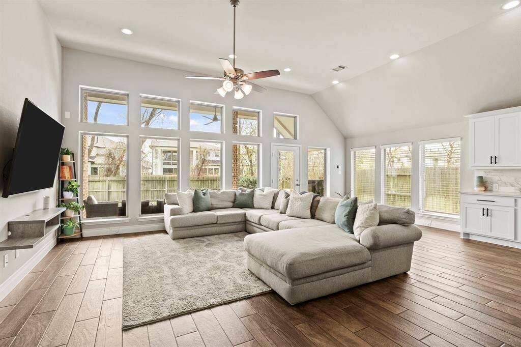A spacious, open-concept living area featuring floor-to-ceiling windows, and a ceiling fan, bringing in tons of natural light.