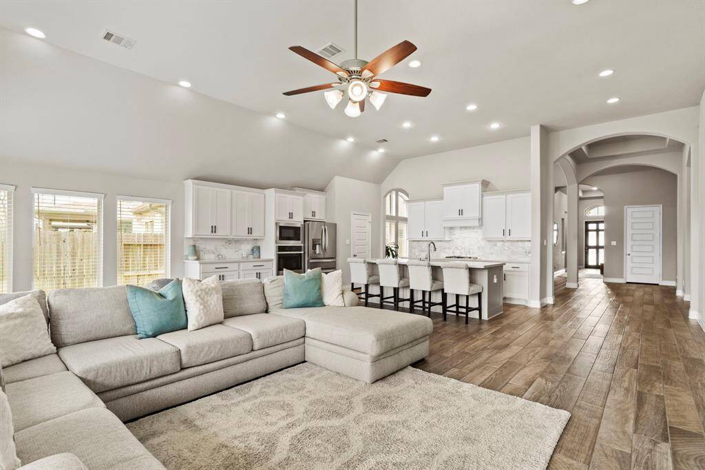 A wide view connecting the living space with the bright, modern kitchen, highlighting the arched hallway and open design.