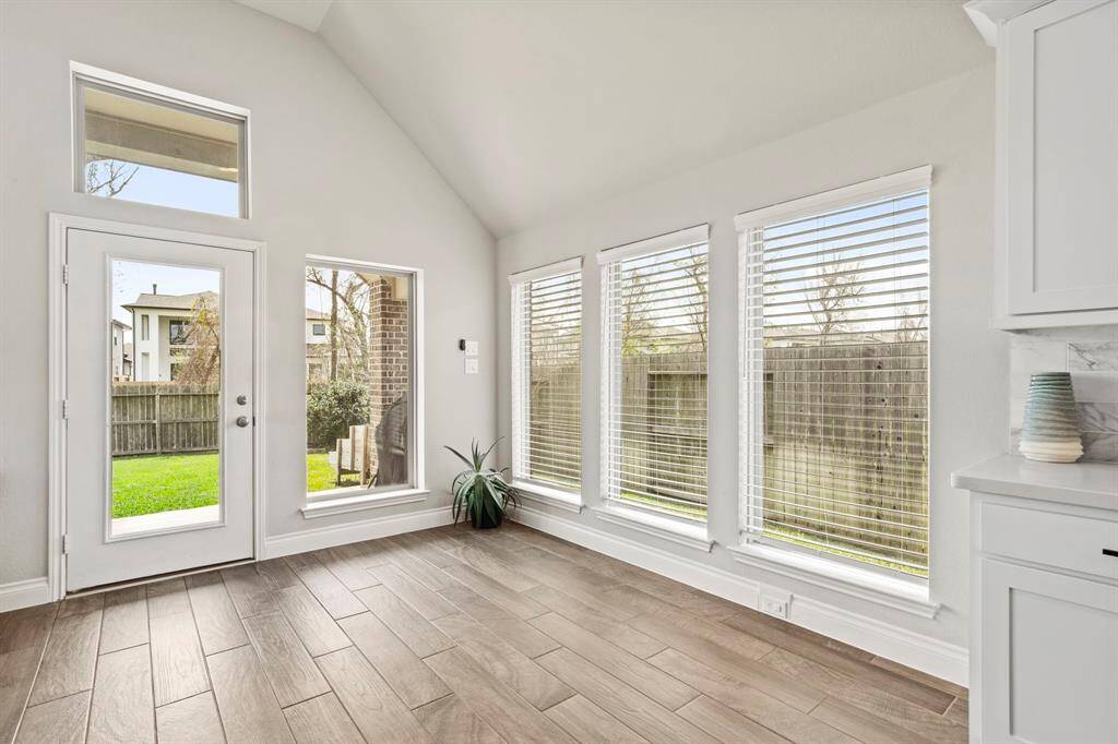 A bright space with full window walls and door access to the backyard—perfect for a breakfast area or reading nook.