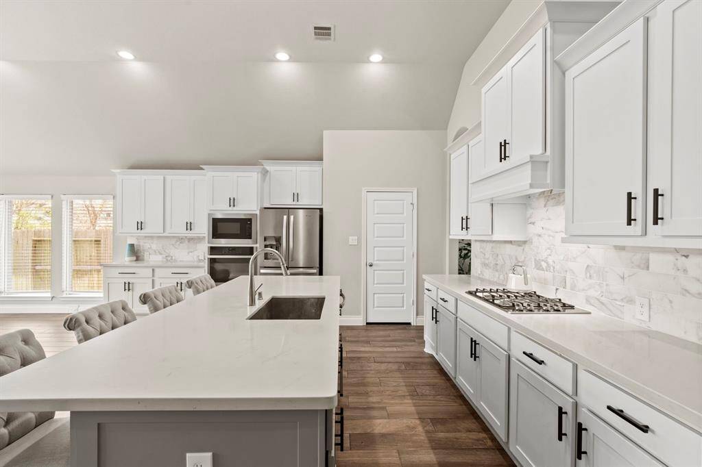 Focuses on the cooking space and storage, showing the built-in microwave and oven with ample cabinetry and prep area.