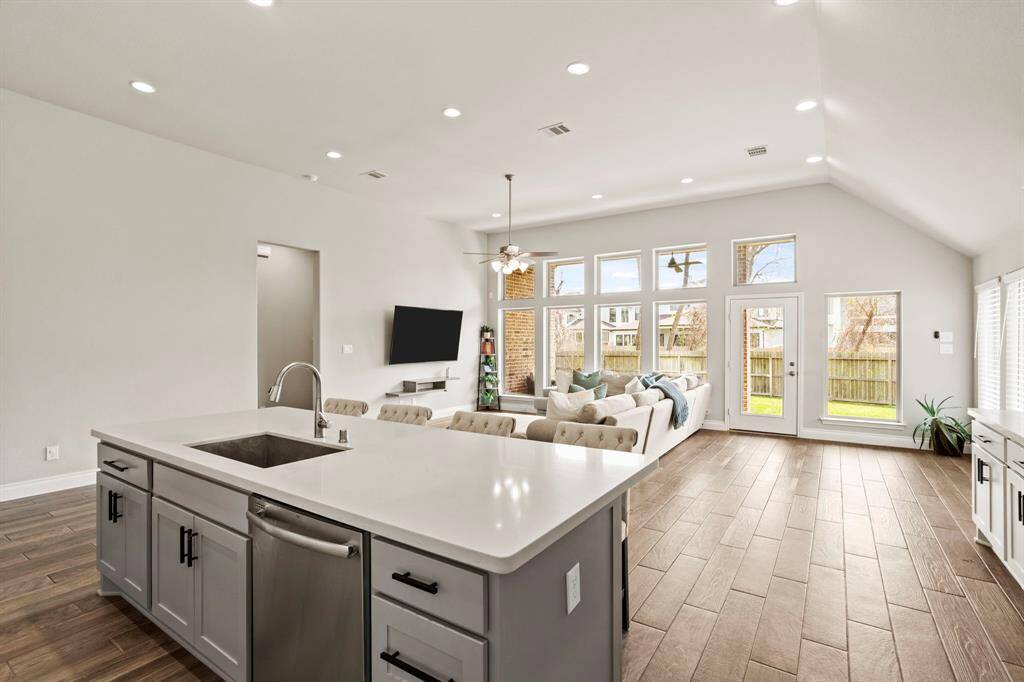 Open layout showing the kitchen flowing seamlessly into the living room, featuring large windows and abundant natural light.