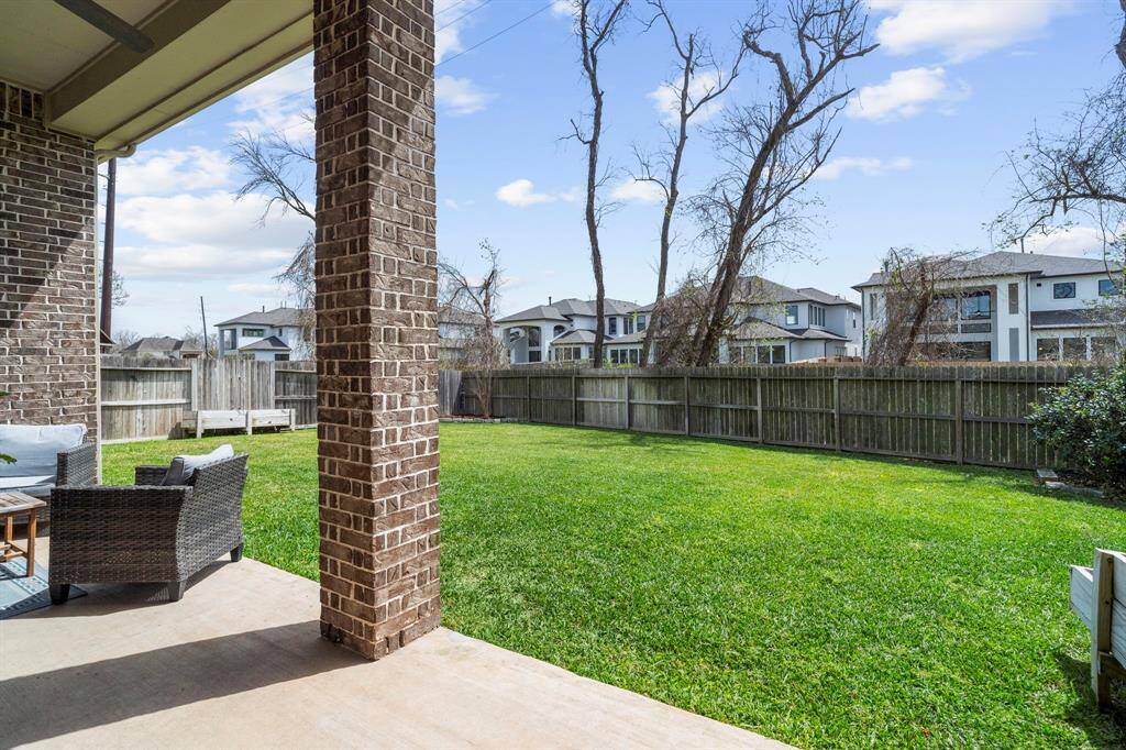 Expansive fenced-in backyard with lush green grass and privacy fence, viewed from the patio.