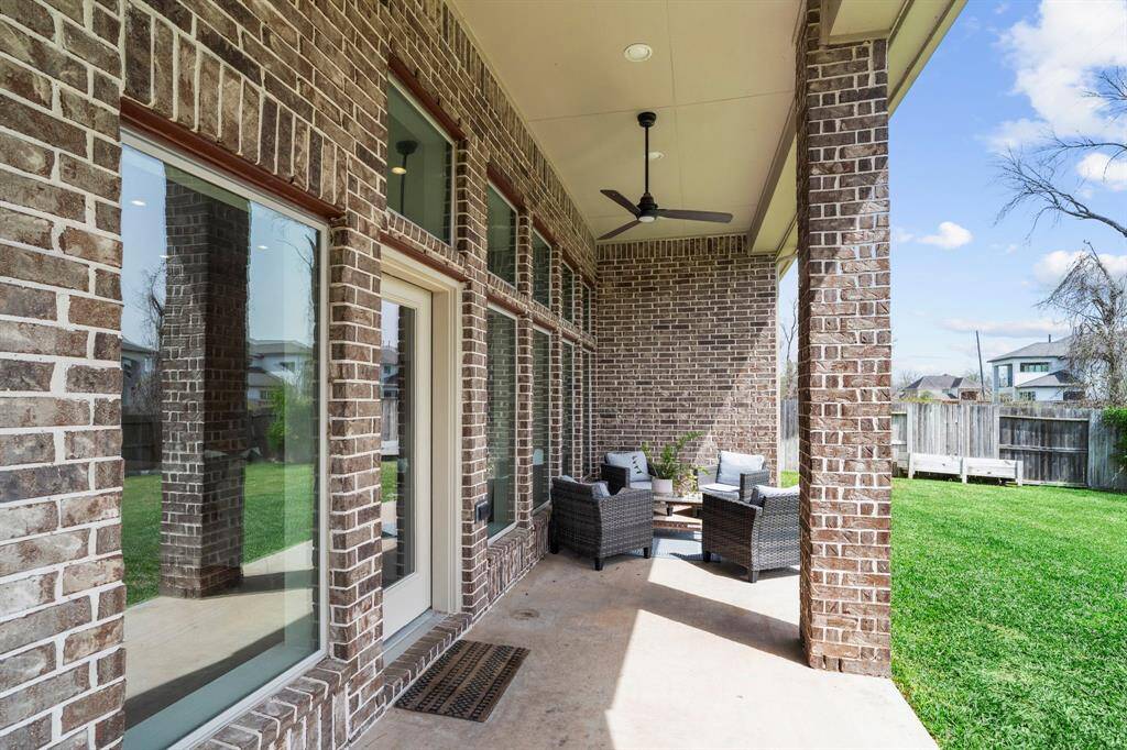 Covered back patio with ceiling fan, ideal for outdoor relaxation.