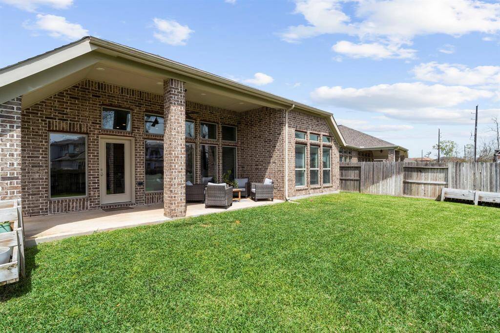 Side angle of the backyard and rear exterior, showing multiple large windows and patio.