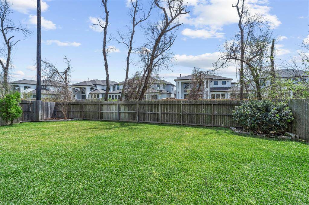 Straight-on view of the back fence line and mature trees beyond, highlighting backyard privacy.