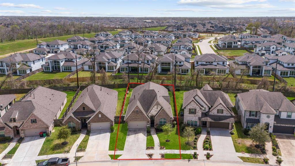Aerial view of the property showing driveway, roofline, and surrounding homes.