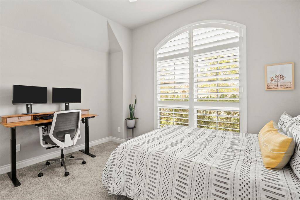 A bright bedroom with white plantation shutters add elegance to the arched window.