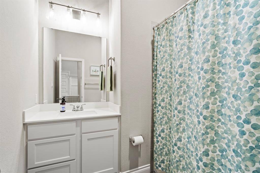 A neutral-toned bathroom featuring a simple white vanity, toilet, and a shower.