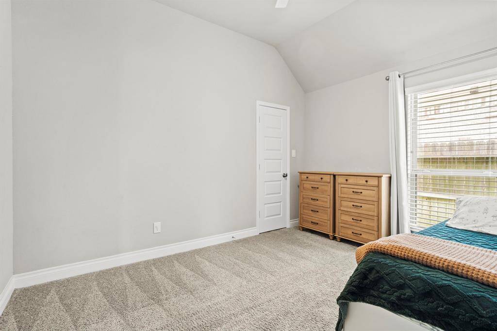 Another well-lit bedroom with beige carpet, and a large window bringing in tons of light! The space is minimal and inviting.