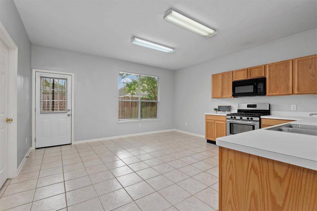 Another view of the kitchen with hardy tile flooring. There is a door that leads to the back yard and deck- perfectly situated for family BBQs.