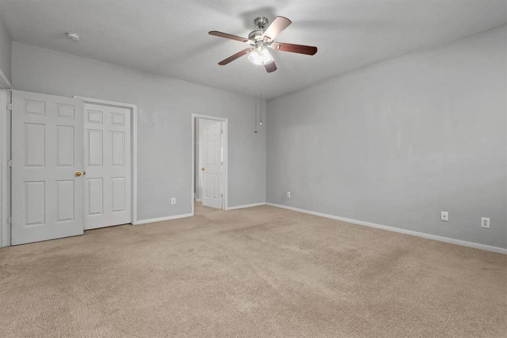 Moving into the primary suite which is towards the back of the home. This room is plenty big for your king-sized bedroom furniture set. The middle door here leads to the enormous walk-in closet.