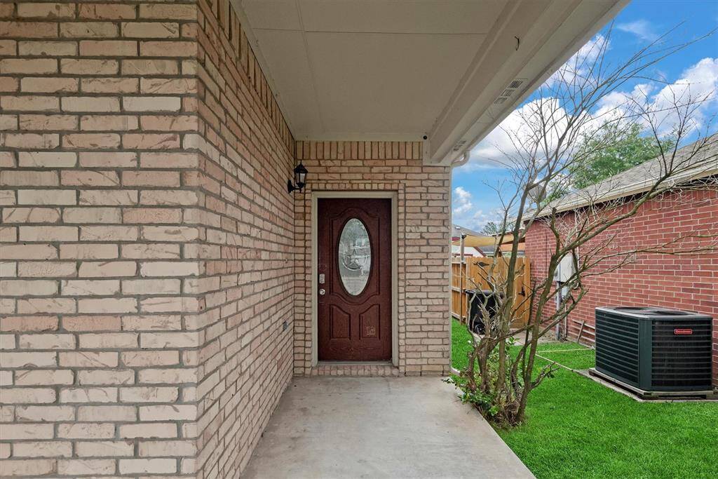 Back on the front porch, there is a covered, welcoming entry way with attractive brick and a pretty leaded glass door.