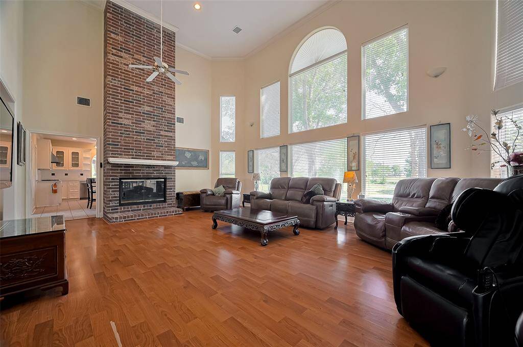 Living room with high ceilings and wall of windows.  Double sided fireplace from living to kitchen.