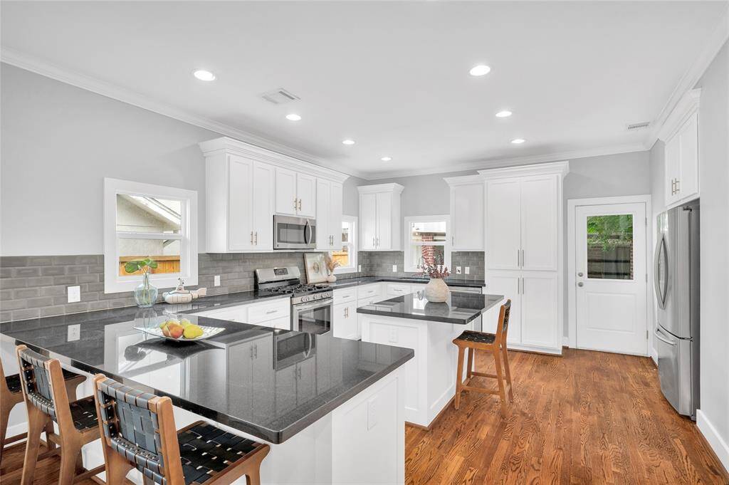 The kitchen has soft close drawers, stainless steel appliances, gas range, and counter seating. The door leads to the back yard.