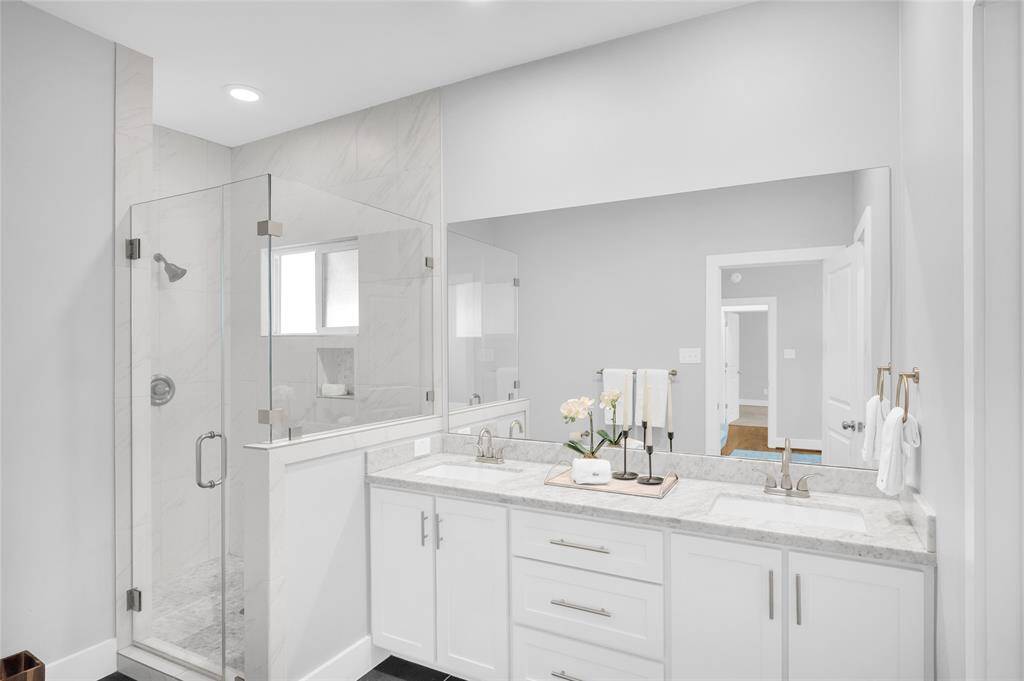 Primary bath with dual sinks seamless shower and classic white marble counters.