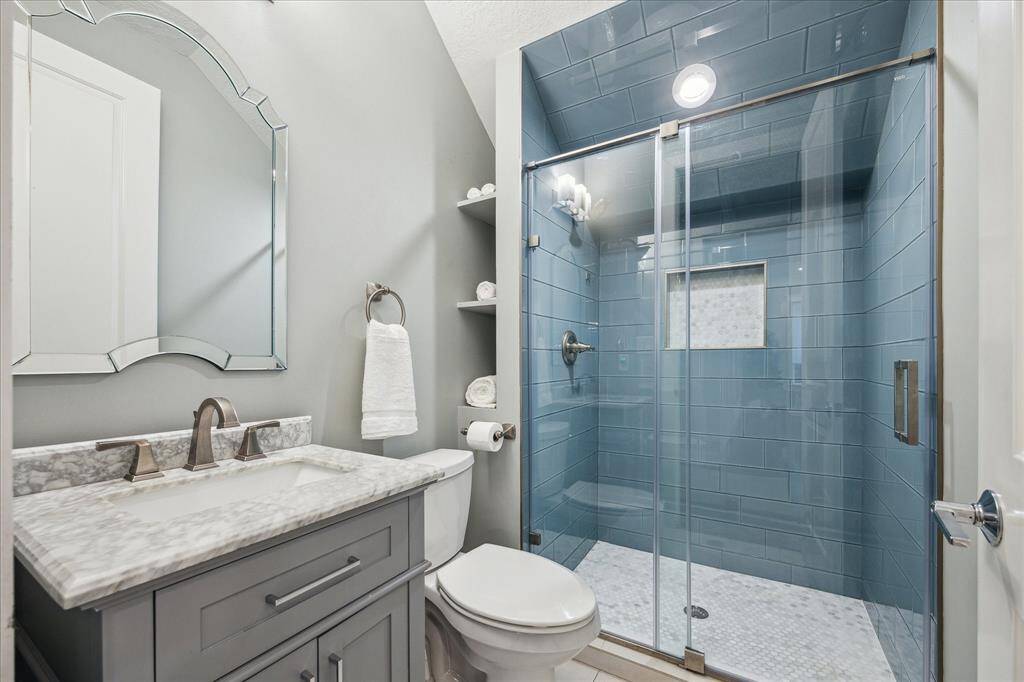 DOWNSTAIRS BATH - Full bathroom on the first floor features marble countertops and a walk-in shower with decorative tile accents.