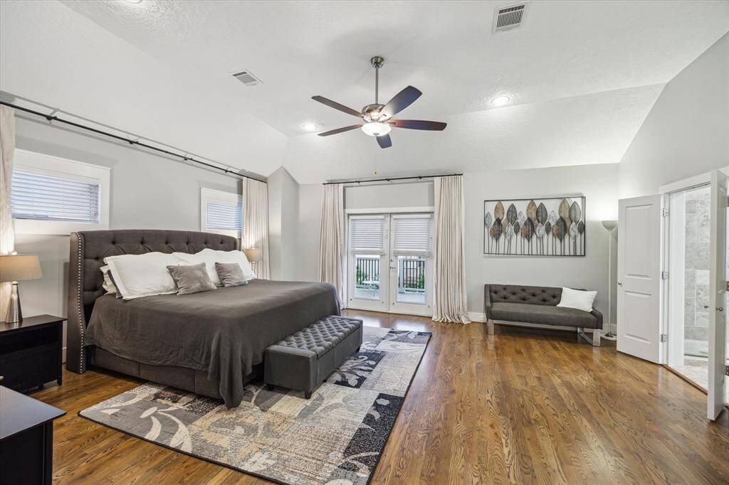 PRIMARY BEDROOM II - Hardwood floors, custom window treatments and French doors opening to balcony.