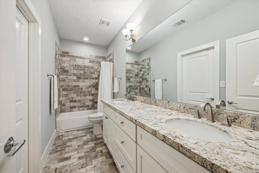 BATHROOM - En-suite bathroom with double sinks, stone tile, granite countertops and tub/shower combo.